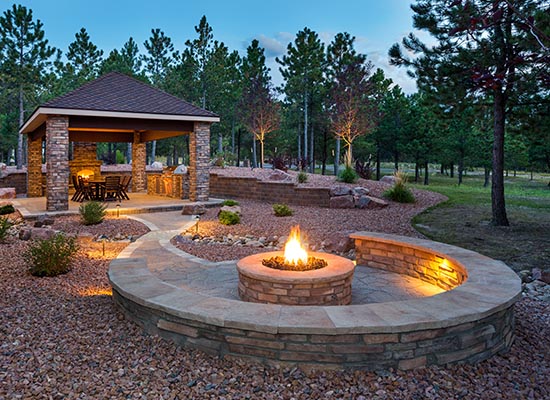 Stone fire pit with seating wall on a paver patio at dusk