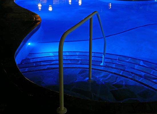Colored LED lighting outlining a swimming pool at dusk