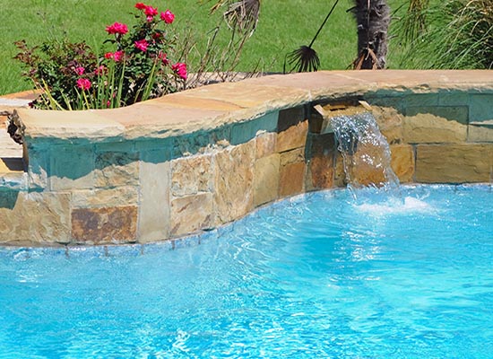 Sheer waterfall spilling into a bright blue pool