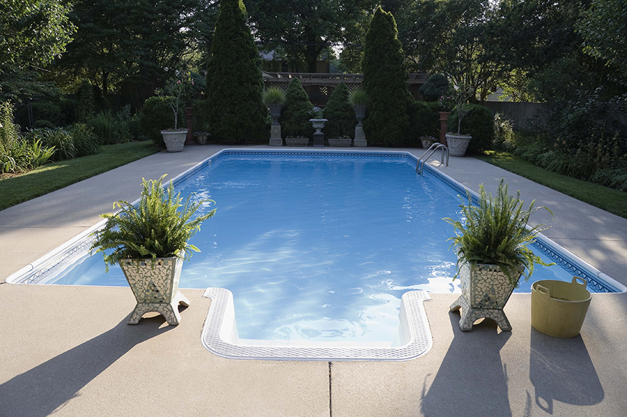 Rectangular inground pool with concrete deck and landscaped surround